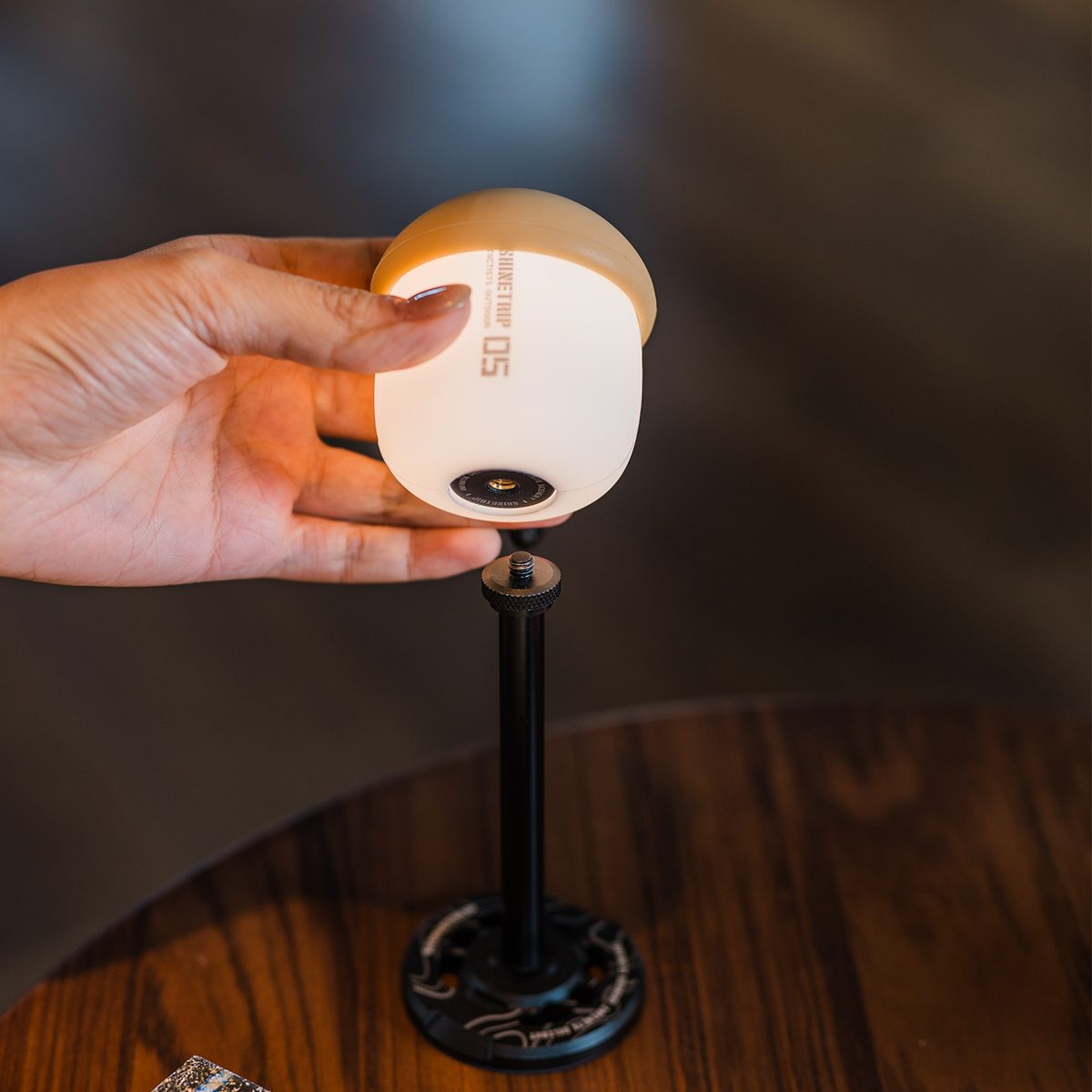 A hand fitting the A61 Acorn Lamp onto the 1/4-inch thread of a black light stand