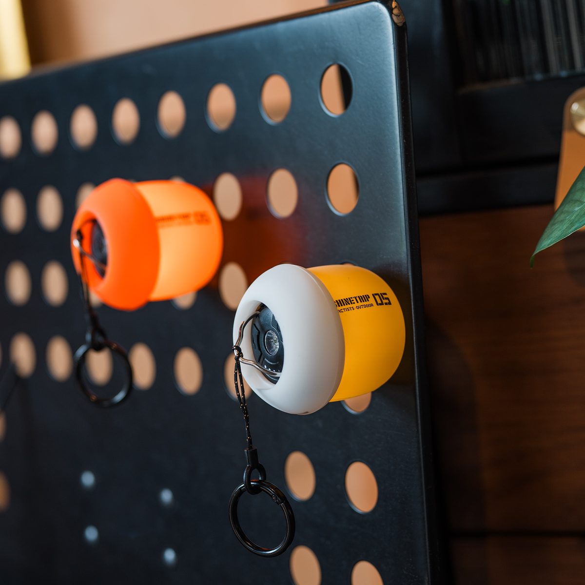Two A61 Acorn Lamps with orange and white shades attached magnetically to a black steel pegboard