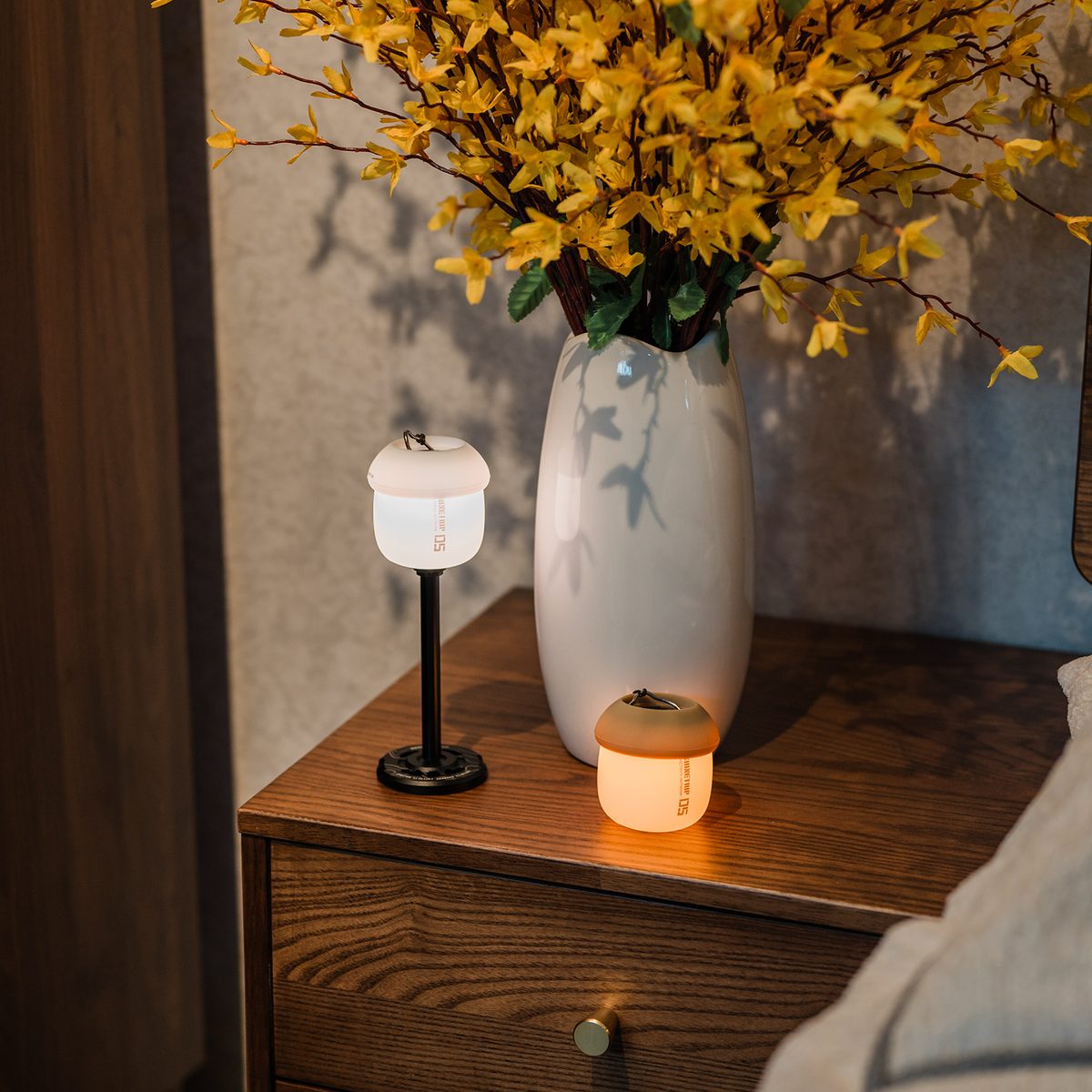A61 Acorn Lamps on a wooden nightstand beside a vase of yellow flowers